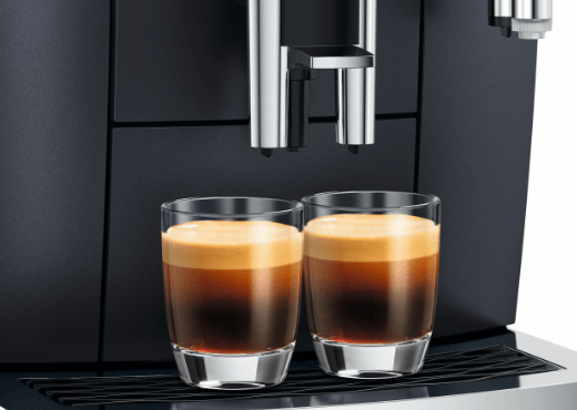 2 szklanki z kawą espresso stojące na obudowie ekspresu Jura