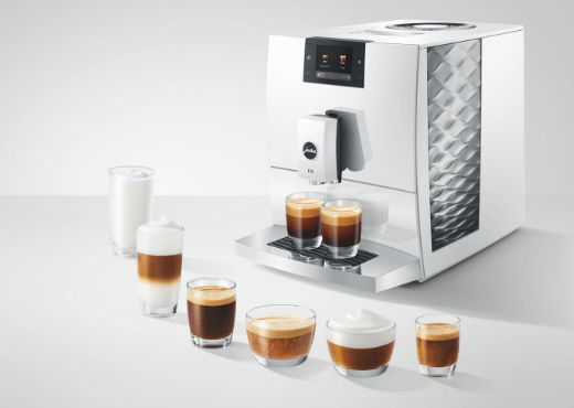 Ekspres Jura z sześcioma napojami obok, w tym espresso, cappuccino, latte oraz szklanka ciepłego mleka.