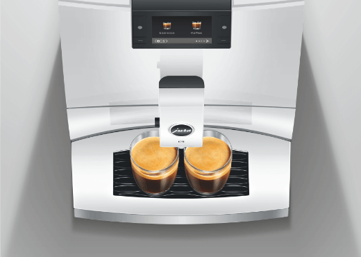 Zbliżenie ekspresu Jura z dwoma filiżankami świeżo zaparzonego espresso.