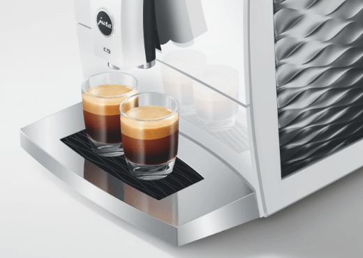 2 szklanki z kawą espresso stojące na obudowie ekspresu Jura