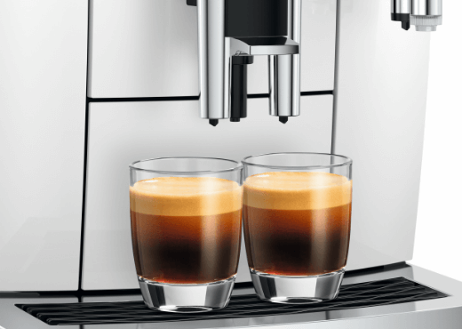 2 szklanki z kawą espresso stojące na obudowie ekspresu Jura